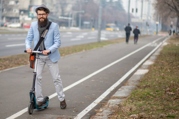 istock Young businessman with a beard smiling on kick scooter 1129070992