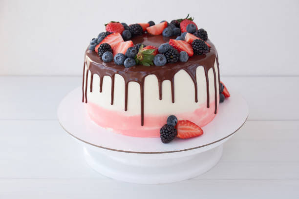 istock Cake with chocolate, decorated with various berries on a white table. 1129074933