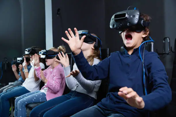 Photo of Enthusiastic children in virtual reality glasses in quest room