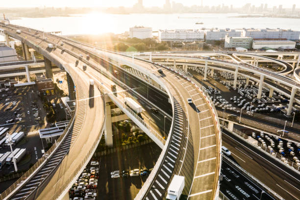 海に向かって高速道路。夕日に照らされた高架道路。逆光で写真を撮る。 - multiple lane highway ストックフォトと画像