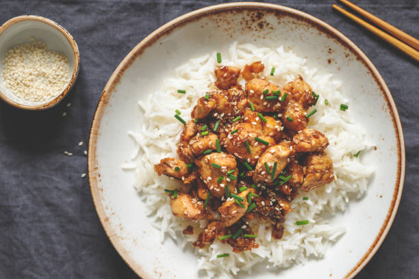 istock Top view on sesame chicken pieces with rice on a ceramic plate. Chinese traditional dish. 1129079513