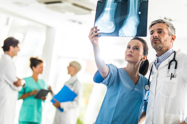 Portrait of traumatologist holding x-ray in hands. Professional physician in white uniform looking carefully at skiagram. Medicine and health care concept