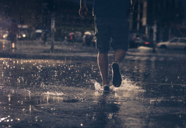istock Back view of unrecognizable man running on a rain. 1129081621