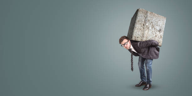 businessman carrying a large and heavy stone on his back - overstrained imagens e fotografias de stock