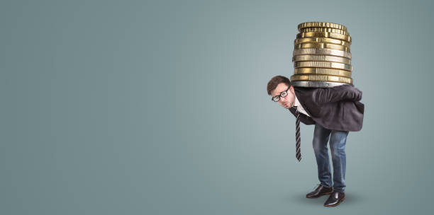 businessman carrying a giant stack of coins on his back - overstrained imagens e fotografias de stock