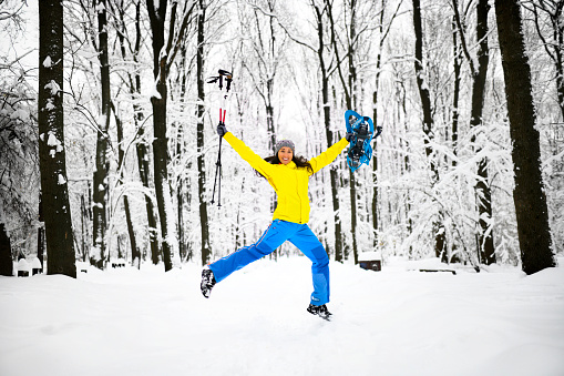 Female hiker jumping merrily in in a frozen forest landscape.