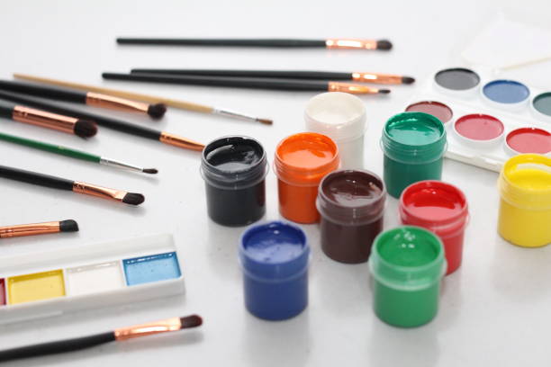 On a white table are brushes, watercolor paints and gouache. The picture is multicolored and very bright. Suitable for artists and students.