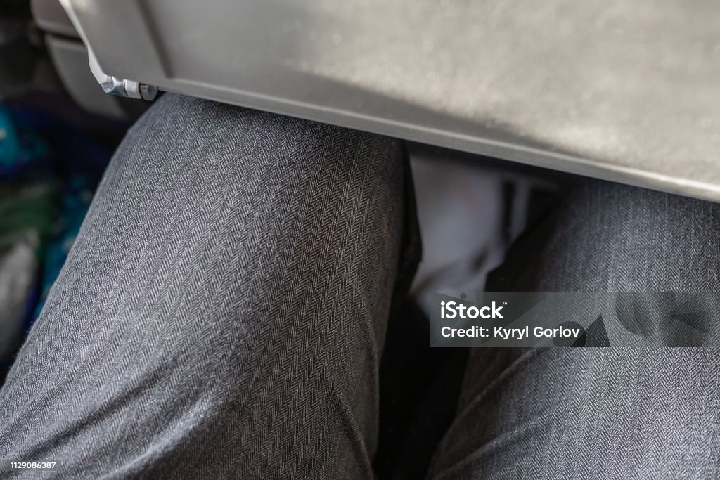 Passenger leg bump into back seat in low-cost commercial airlines. Narrow space for person knee in budget carrier airplane. Cheap tickets and travel Passenger leg bump into back seat in low-cost commercial airlines. Narrow space for person knee in budget carrier airplane. Cheap tickets and travel. Airplane Stock Photo