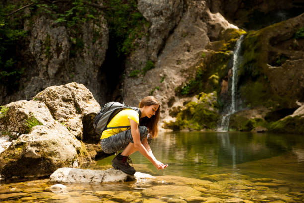 istock active young woman drinking water from a mountain creek on a warm spring day 1129089883