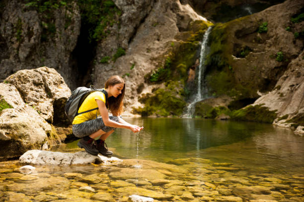 istock active young woman drinking water from a mountain creek on a warm spring day 1129089884