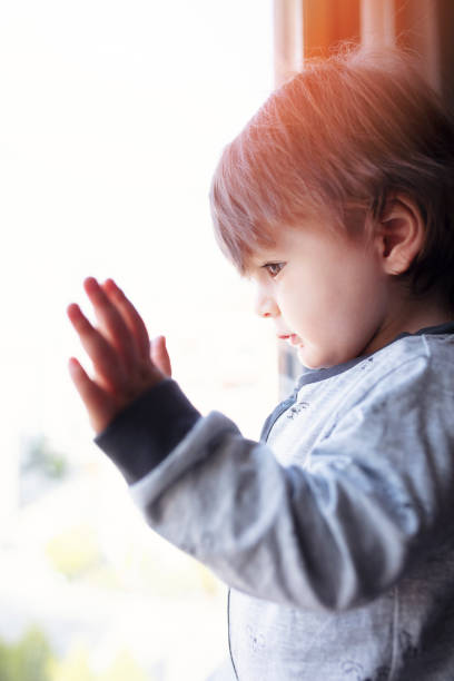 istock Little boy looking out of the window 1129092364