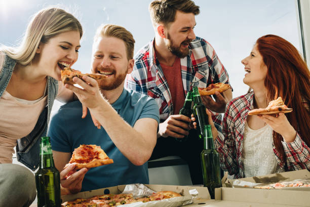 istock Happy couples having fun while eating pizza and drinking beer. 1129093589