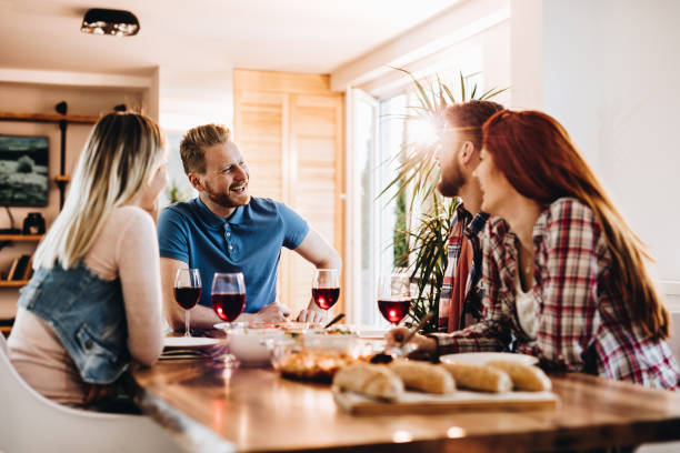istock Young happy people enjoying in conversation at dining table at home. 1129094232