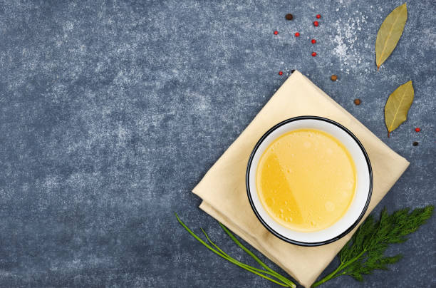 Homemade broth in the bowl on the  grey background.