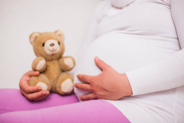 istock Pregnant woman holding teddy bear 1129096030