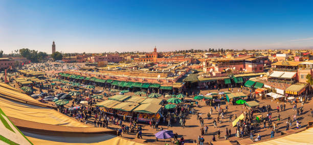 View of the busy Jamaa el Fna market square in Marrakesh, Morocco Marrakech, Morocco - January 11, 2019 : Panorama of the famous Jamaa el Fna market square in Marrakesh, Morocco. This place is also known as Jemaa el-Fnaa and is located in the Medina quarter. djemma el fna square stock pictures, royalty-free photos & images