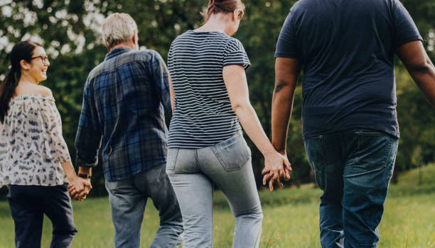 istock Diverse people holding hands and running in the park 1129102783