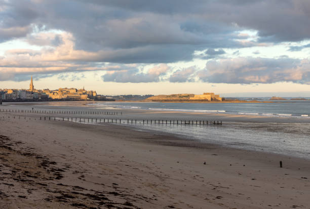 la lumière du matin sur la plage du sillon et la ville fortifiée. saint malo, france, ille et vilaine, côte d'émeraude - beach sunrise waterbreak sea photos et images de collection