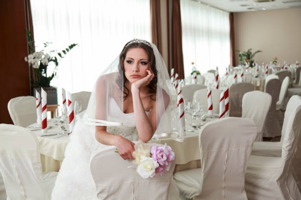 Waiting bride Bride sitting in a ceremony waiting restaurant. Sitting sad with head and flowers in her hands. bride stock pictures, royalty-free photos & images