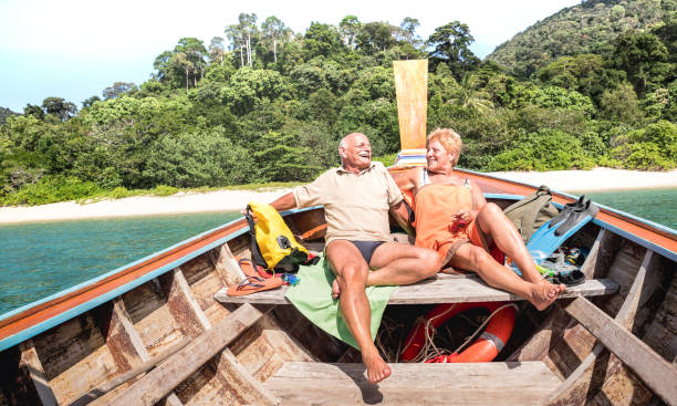 vacanciers de couple de personnes âg�ées relaxant à island hopping tour après exploration de la plage au cours de l’excursion en bateau tuba dans filtre lumineux de la thaïlande - concept active de personnes âgées et voyage en tournée partout dans - phuket province thailand tourist asia photos et images de collection