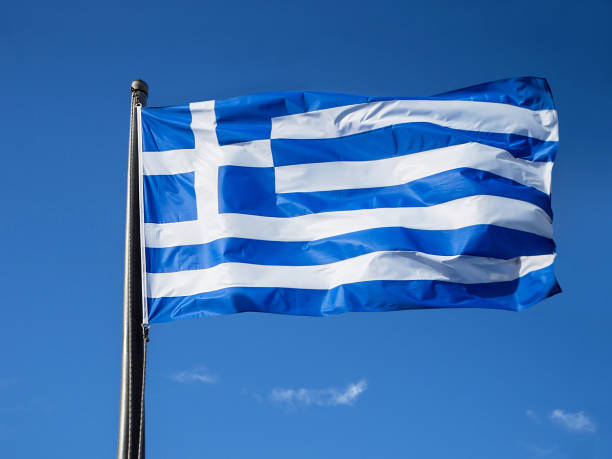 istock Greek flag waving in blue sky in Greece 1129106587