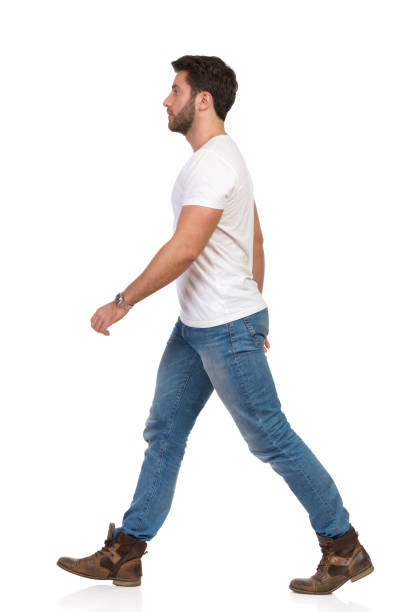 istock Young Man In Jeans And White T-shirt Is Walking Side View 1129108016