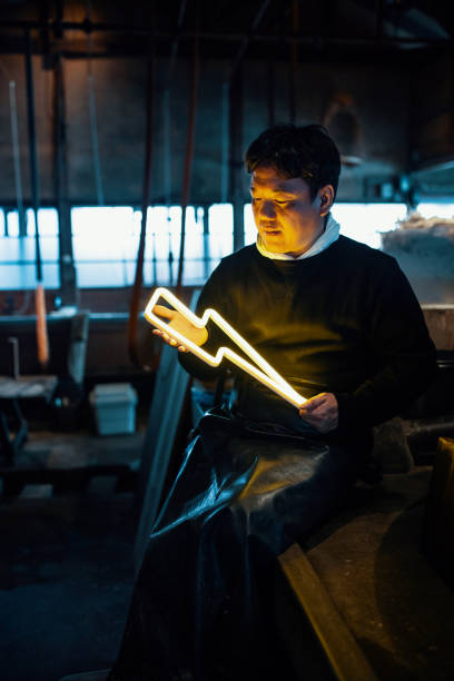 istock Mid adult man holding an illuminated lightning bolt shaped neon light in a factory setting 1129108363