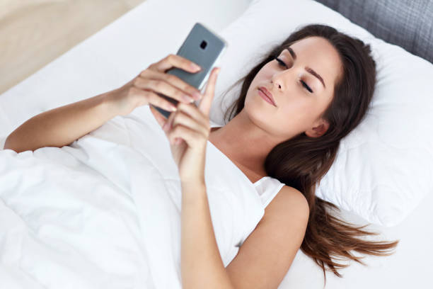 istock Young beautiful woman resting in bed with smartphone 1129108664