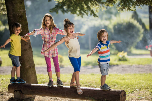 istock Happy little kids having fun while walking on a tree trunk outdoors. 1129109501