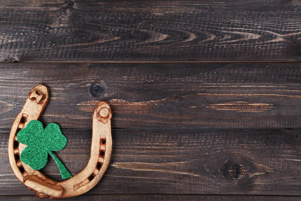 istock St.Patrick's Day. Golden horseshoe with clover leaf on wooden table 1129109800