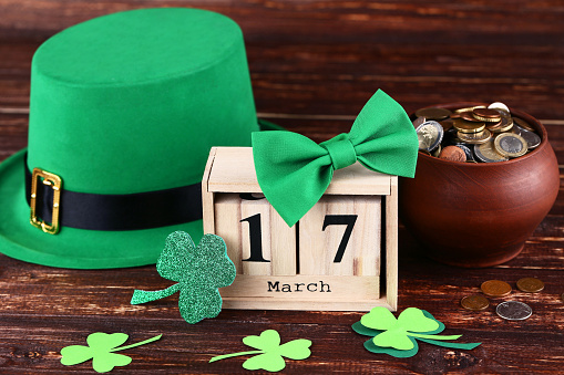 St. Patrick's Day. Green hat with clover leafs, wooden calendar and coins