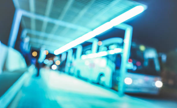 blurred defocused background of bus station terminal at night - abstract concept of transportation with blurry backdrop and copy space - vivid azure filter and tilted composition - bus station imagens e fotografias de stock