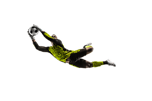 The one male soccer player goalkeeper catching ball in jumping. Silhouette of fit man with ball isolated on white studio background