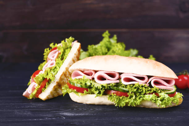 istock Tasty sandwiches on black wooden table 1129112175