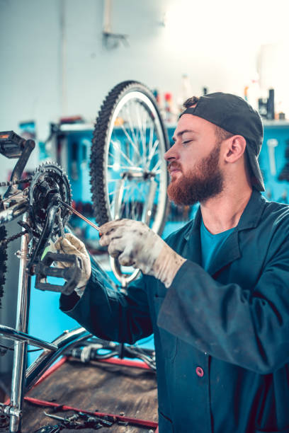istock Young Bearded Mechanic Fixing Chain Gear With Screwdriver 1129113732
