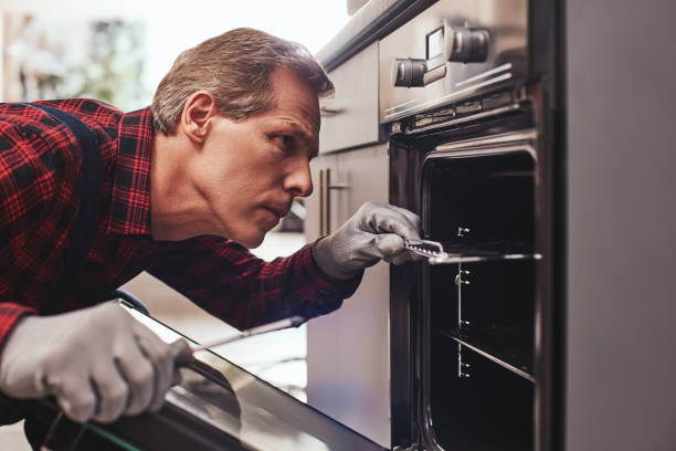 istock He knows how to solve this problem. Close-up of repairman examining oven 1129117238