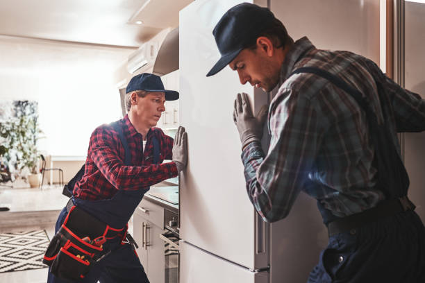 Easy to solve. Young men mechanics checking refrigerator stock photo