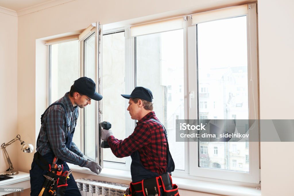 Quality light. Construction workers installing new window in house Quality light. Construction workers installing new window in house together Window Stock Photo