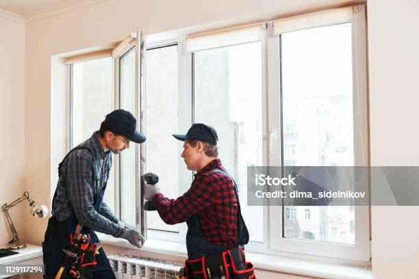 Quality Light Construction Workers Installing New Window In House Stock Photo - Download Image Now