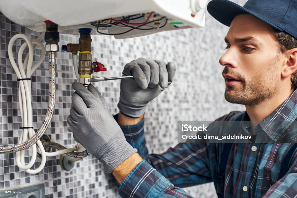 Wrench always with you. Worker set up electric heating boiler at home bathroom Wrench always with you. Worker set up electric heating boiler at home. Close-up of young handyman Plumber Stock Photo