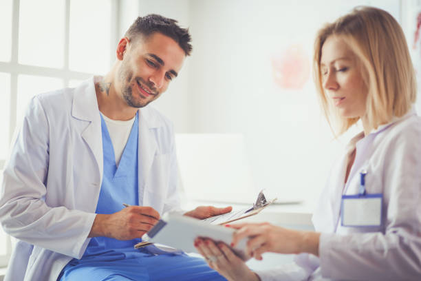 istock Handsome doctor is talking with young female patient and making notes while sitting in his office 1129119506