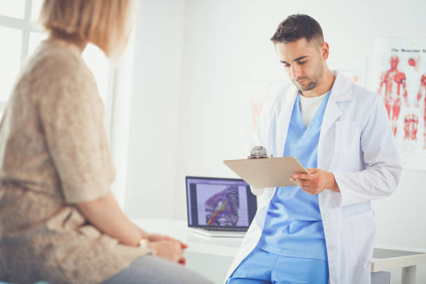 istock Handsome doctor is talking with young female patient and making notes while sitting in his office 1129119538