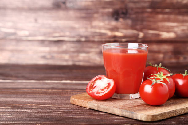istock Tomato juice in glass on brown wooden table 1129122947