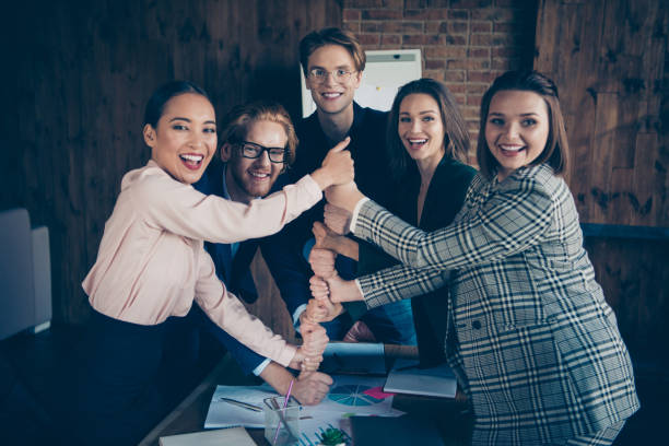 istock Five stylish cheerful experts executive managers staff putting fists on each other gathering result achievement corporate resources recruitment at modern industrial loft interior work place station 1129126102