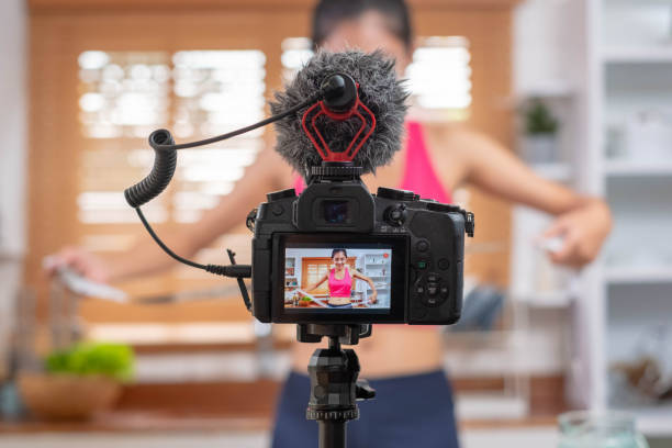istock close up at camera while asian woman blogger recording a video tutorial how to loose weight and get healthy. Influencer lifestyle concept. 1129128656