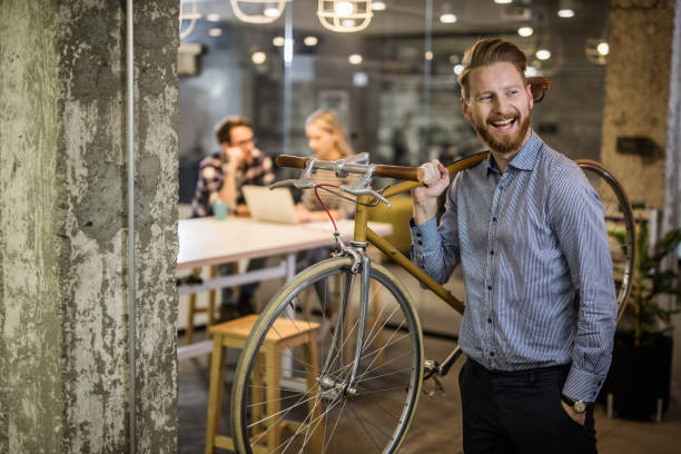 istock Happy businessman carrying his bicycle while leaving the office after work. 1129129216