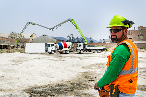 Concrete pump operator with remote control for boom pump truck at construction site.