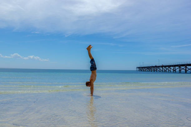 A Man doing a handstand on a Tropical White Sand Beach of Western Australia