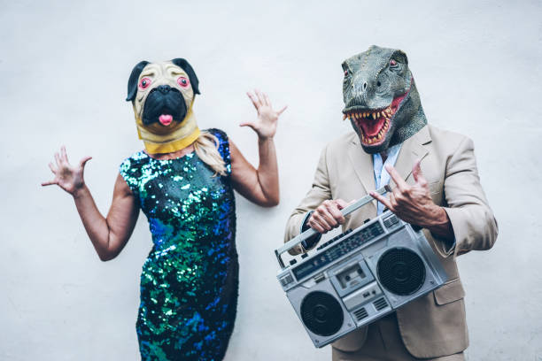 crazy senior couple dancing for party wearing t-rex and chicken mask - old trendy people having fun listening music with boombox stereo - absurd and funny trend concept - focus on dino face - white dog audio imagens e fotografias de stock