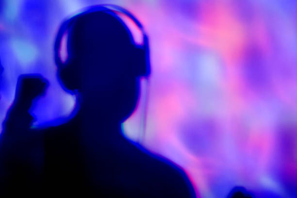 The vocalist records a song in a high-quality studio, using headphones and hand movements.